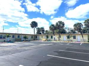 a parking lot in front of a building with palm trees at Pineapple Shores Retro Inn 3 in Daytona Beach