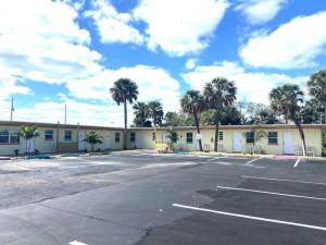 a parking lot in front of a building with palm trees at Pineapple Shores Retro Motel 9 in Daytona Beach