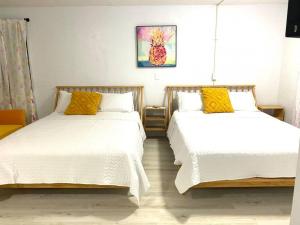 デイトナビーチにあるPineapple Shores Retro Inn 4の白と黄色の枕が置かれた部屋にベッドが2つある
