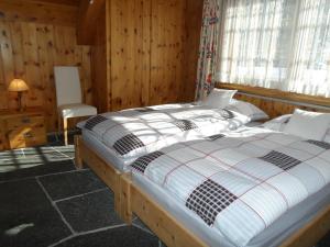 una camera con due letti in una stanza con pareti in legno di Chalet Atelier a Davos