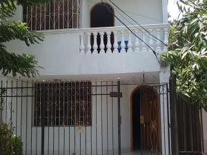 a white house with a gate and a balcony at Room in House - Taminaka Hostel in Santa Marta - Private Room in Santa Marta