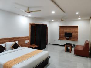 a bedroom with a bed and a couch and a tv at Sadanand's Highway Inn, Tumkur in Tumkūr