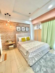 a bedroom with a bed and a brick wall at Two Palm Tree Villas in Manila
