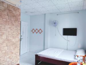 Habitación blanca con cama y TV de pantalla plana. en Nhà nghỉ Thành Lợi, en Ấp Rạch Mẹo