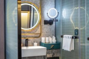 een badkamer met een wastafel en een spiegel bij Percent Hotel Yangshuo in Yangshuo