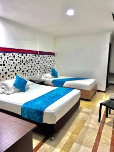 um quarto de hotel com duas camas com almofadas azuis em Hotel Ingenio Reina Isabel em Cali