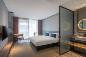 Percent Hotel Yangshuo في يانغتشو: غرفة الفندق بسرير ومغسلة