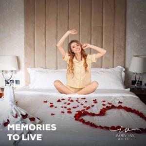 una chica está sentada en una cama con corazones rojos en Ivory Inn Hotel Doha Qatar, en Doha