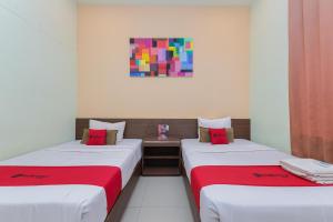 two beds sitting next to each other in a room at RedDoorz near Alun Alun Madiun in Madiun