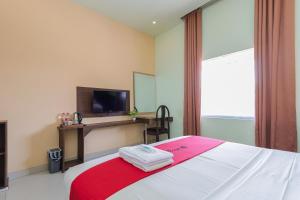 a bedroom with a bed with a red and white blanket at RedDoorz near Alun Alun Madiun in Madiun