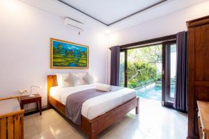 a bedroom with a bed and a large window at Villa Kubu Arya by Supala in Ubud