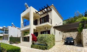 a white house with a car parked in front of it at Villa Seashell, Private Pool and Magnficent View in Ravdhoúkha