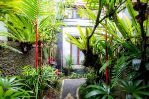 a garden with palm trees and plants in front of a building at Villa Kubu Arya by Supala in Ubud