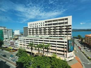 a large white building with palm trees in front of a street at Hotel Capital Kota Kinabalu in Kota Kinabalu