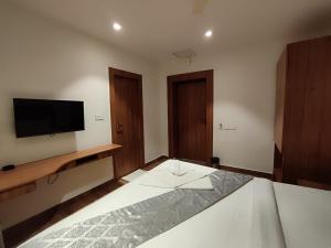 um quarto com uma cama e uma televisão de ecrã plano em STAYMAKER Hotel Mohan Palace em Baharampur