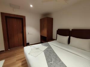 1 dormitorio con 1 cama grande con sábanas blancas en STAYMAKER Hotel Mohan Palace, en Baharampur