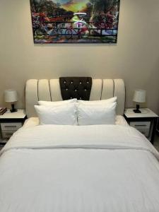a bedroom with a white bed with two tables with lamps at غرفة صغيرة ساحرة in Riyadh