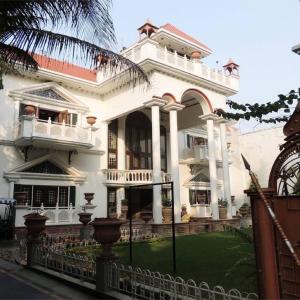 uma grande casa branca com uma cerca em frente em Kunjpur Guest House em Allahabad