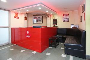 um bar com um sofá preto e uma parede vermelha em Kalighat em Ālīpur