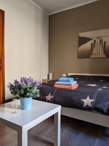 um quarto com uma cama e uma mesa com flores roxas em Verbania Centro Storico 2 camere em Verbania