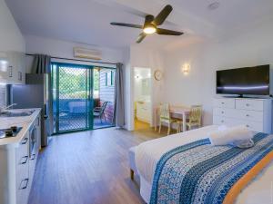 a bedroom with a bed and a kitchen with a table at Boat Harbour Studio Apartments and Villas in Hervey Bay