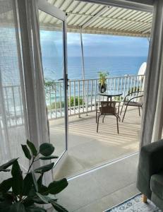 a room with a balcony with a table and the ocean at Shore Break, 1 bedroom apartment in Umdloti
