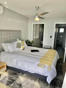 a bedroom with a large white bed with a ceiling fan at Shore Break, 1 bedroom apartment in Umdloti