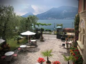 un patio con tavoli, sedie e vista sull'acqua di Villa Torre - Atmosfera Romantica a Brenzone sul Garda