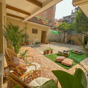 un patio con sillas y césped con plantas en The Melo pomelo courtyard. ( Right in between Thamel and basantapur durbar square) en Katmandú