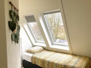 a bedroom with a bed and two windows at Maralong Noordwijk in Noordwijk