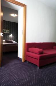 sala de estar con sofá rojo y cama en Hotel George, en Nadarzyn