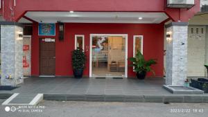a red building with a door and plants in front at Hotel Casa Reo in Kampong Bagan Lalang