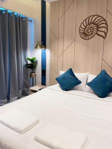 1 dormitorio con 1 cama blanca grande con almohadas azules en Carapace Huahin - Khaotao (ที่พักติดทะเล), en Khao Tao