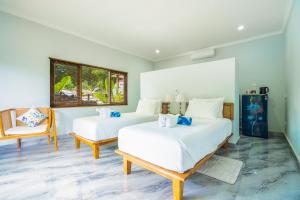 1 dormitorio con 2 camas y 1 silla en Lunar Dive Resort: Bamboo Villas en Kubu