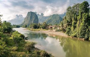 a river with trees and mountains in the background at Vang Vieng Sunset Guesthouse & Restaurant in Vang Vieng