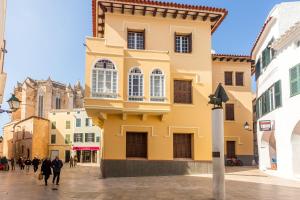 um edifício amarelo no meio de uma rua em Ses Andrones 3 em Ciutadella