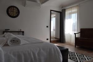 a white bedroom with a bed and a clock on the wall at Cascina Tre Botti in Agliano Terme