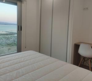 a bedroom with a bed and a view of the ocean at Apartamentos O Grove Awa Bay in O Grove