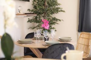 una mesa con platos y vasos y un jarrón con flores rosas en Centre Ville - Cocon Des Bois - Gare, en Saverne