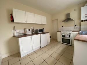a kitchen with white cabinets and a stove at Nice Living Serviced Accommodations 5 in Coventry