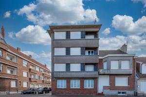 a tall brick building with white windows next to buildings at Banc des Flandres in Bray-Dunes +4 photos