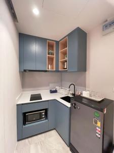 una pequeña cocina con armarios azules y nevera. en Carapace Huahin - Khaotao (ที่พักติดทะเล), en Khao Tao