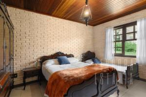 a bedroom with a large bed in a brick wall at Casa Merlot com Lareira Quadra e Vista para Lago in Rancho Queimado