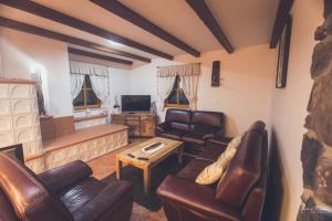 a living room with leather furniture and a tv at Holiday Mountain House Rupicapra in Kostel