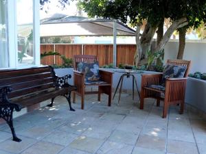 eine Terrasse mit 2 Bänken, einem Tisch und einem Sonnenschirm in der Unterkunft The Boston Guest House in Bellville