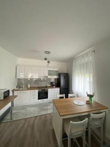 uma cozinha com armários brancos e uma mesa e cadeiras em Villa LIPI - Home Away from Home em Balatonszemes