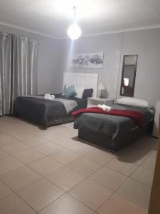 um quarto com 2 camas e um espelho em Stay at Home Airport Lodge em Kempton Park