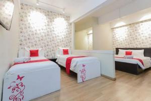 a bedroom with two beds with red and white at RedDoorz Plus at Riverside Malang in Malang