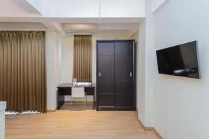 a room with a door and a desk and a television at RedDoorz Plus at Riverside Malang in Malang