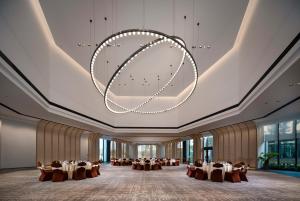Yongxiu的住宿－吴城远洲酒店，一个带桌椅和大吊灯的大型宴会厅